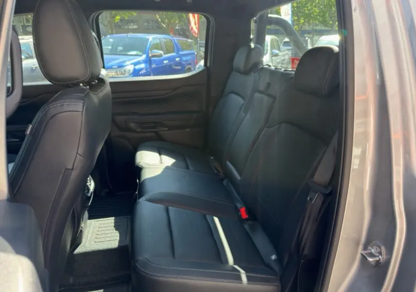 Vue intérieure arrière droite du Ford Ranger gris iconic, montrant les sièges en cuir noir et les ceintures de sécurité.