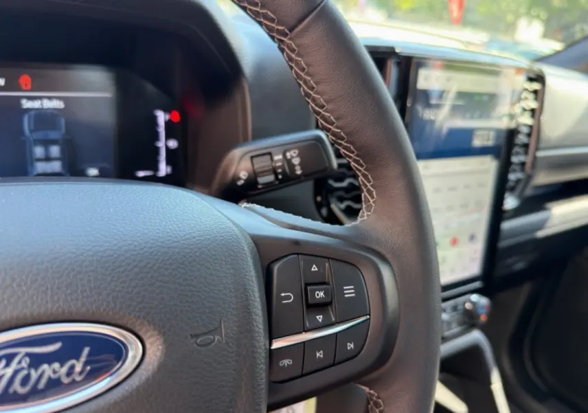 Gros plan sur le volant cuir multifonctions du Ford Ranger 2026, avec tableau de bord numérique et écran tactile vertical.