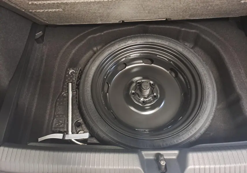 Roue de secours à encombrement réduit avec cric dans le coffre d'une Volkswagen Golf 2.0 TDI blanc Oryx nacré.