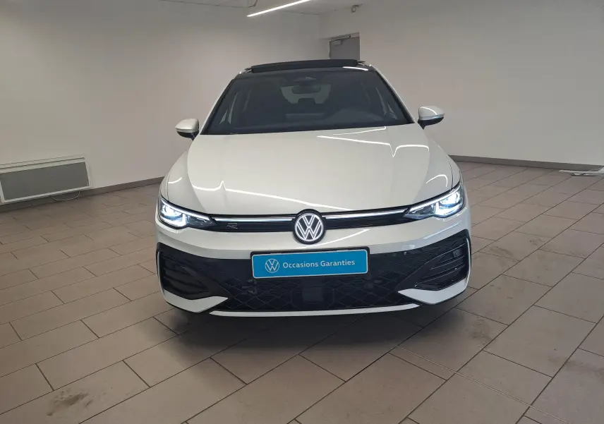 Volkswagen Golf 2.0 TDI 150 DSG7 R-Line blanc oryx nacré vue de face avec phares LED allumés dans un intérieur.