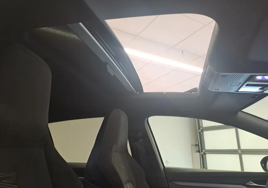 Vue intérieure de la Volkswagen Golf 2.0 TDI 150 R-Line avec toit ouvrant panoramique et sièges sport noirs.