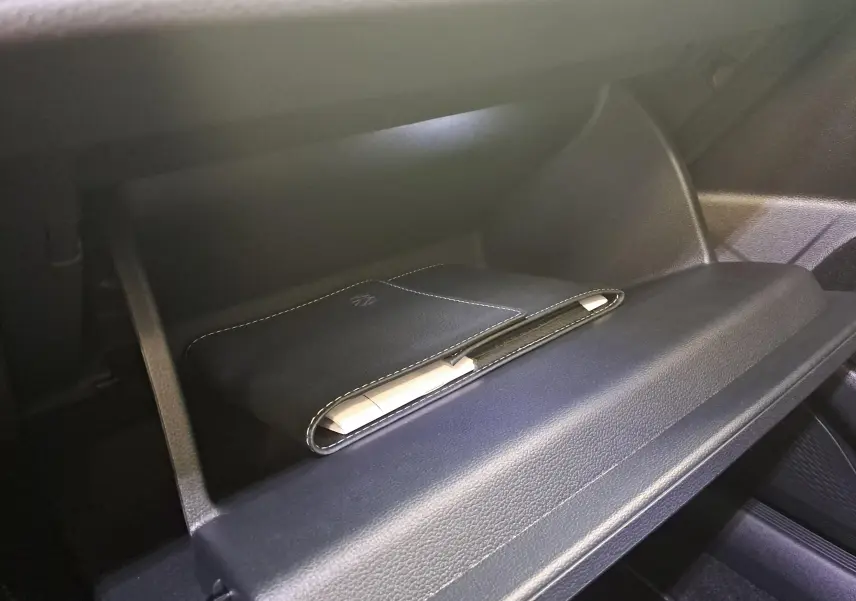Gant de poche noir avec logo VW dans la boîte à gants d'une Volkswagen Golf 2.0 TDI blanche, vue intérieure.