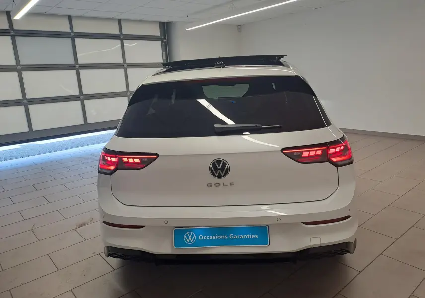 Vue arrière d'une Volkswagen Golf 2.0 TDI blanche avec toit ouvrant noir et feux arrière LED 3D allumés dans un garage.