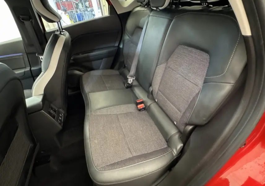 Vue intérieure arrière côté droit du Renault Captur rouge 2024, sièges mixtes tissu et cuir noir.