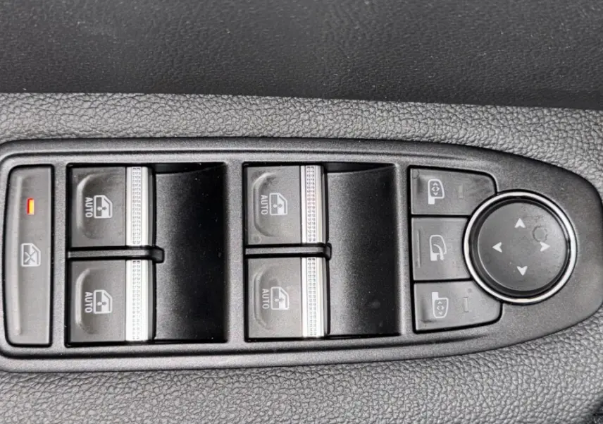 Gros plan sur les commandes de lève-vitres et rétroviseurs côté conducteur du Renault Captur rouge 2024.