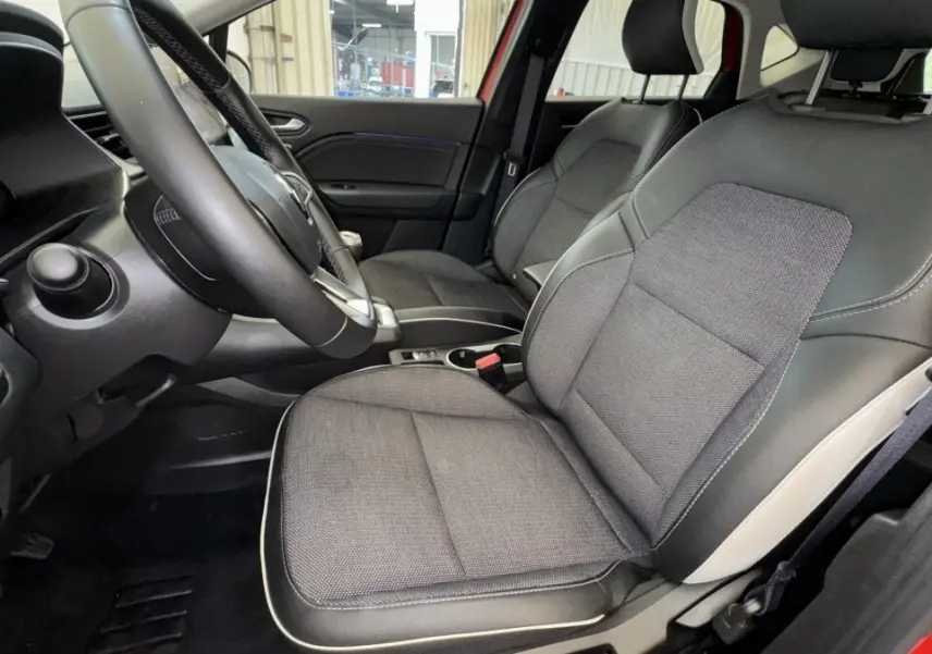 Vue intérieure côté conducteur du Renault Captur rouge 2024, sièges tissu et cuir avec volant multifonctions.