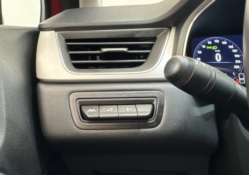 Détail intérieur côté gauche du tableau de bord du Renault Captur rouge 2024 avec commandes d'assistance et affichage numérique.