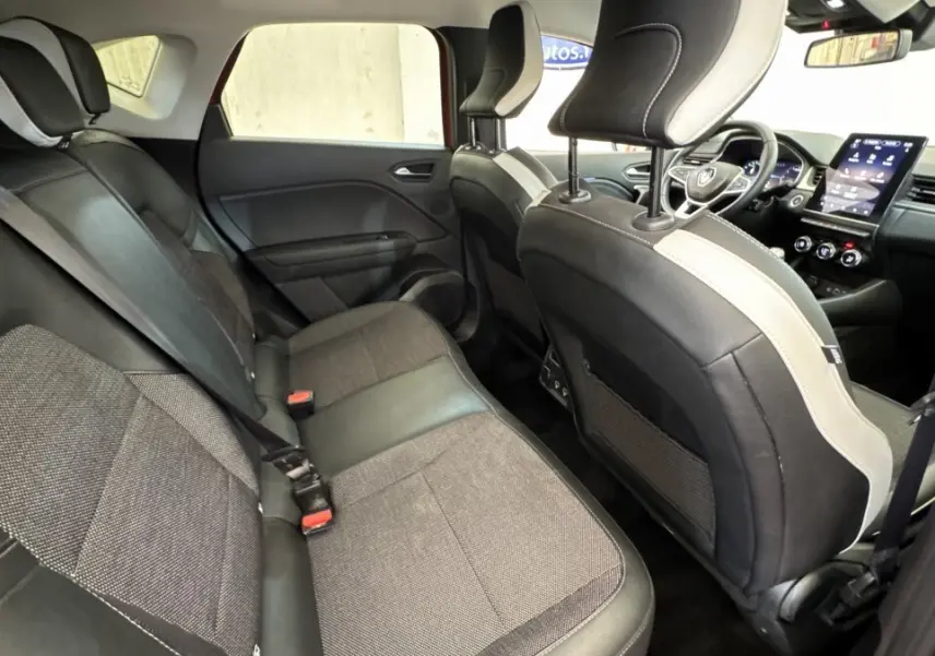 Intérieur arrière du Renault Captur Techno rouge 2024, vue côté gauche avec sièges bi-matière et écran tactile central visible.