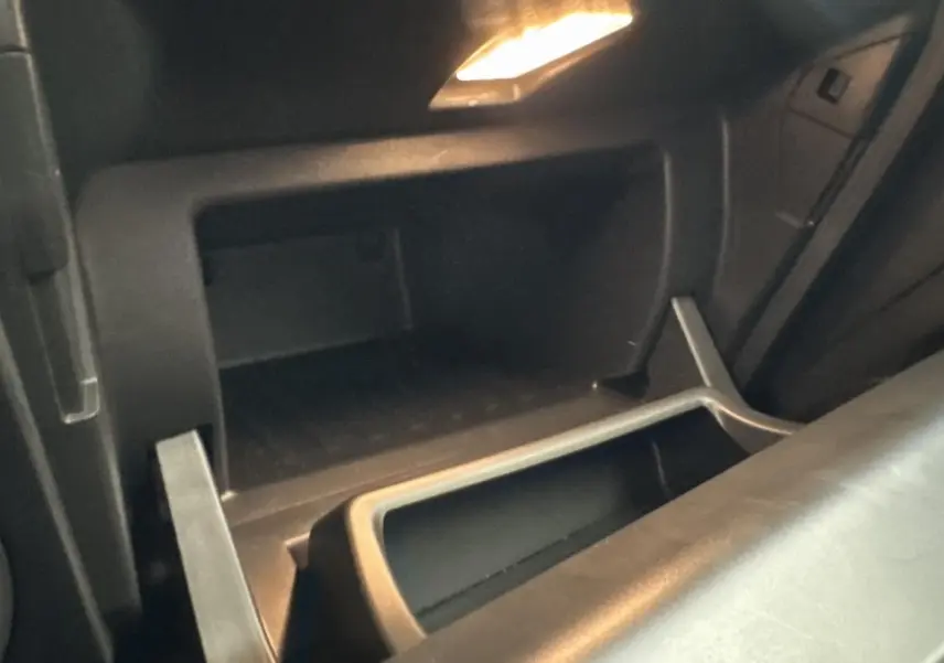 Gros plan sur la boîte à gants ouverte de la Renault Captur 2024, intérieur noir avec éclairage intérieur.