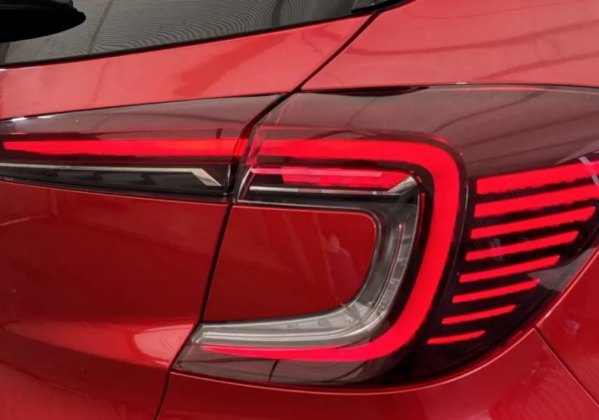 Gros plan sur le feu arrière droit rouge du Renault Captur 2024 finition techno TCe 90, carrosserie rouge.