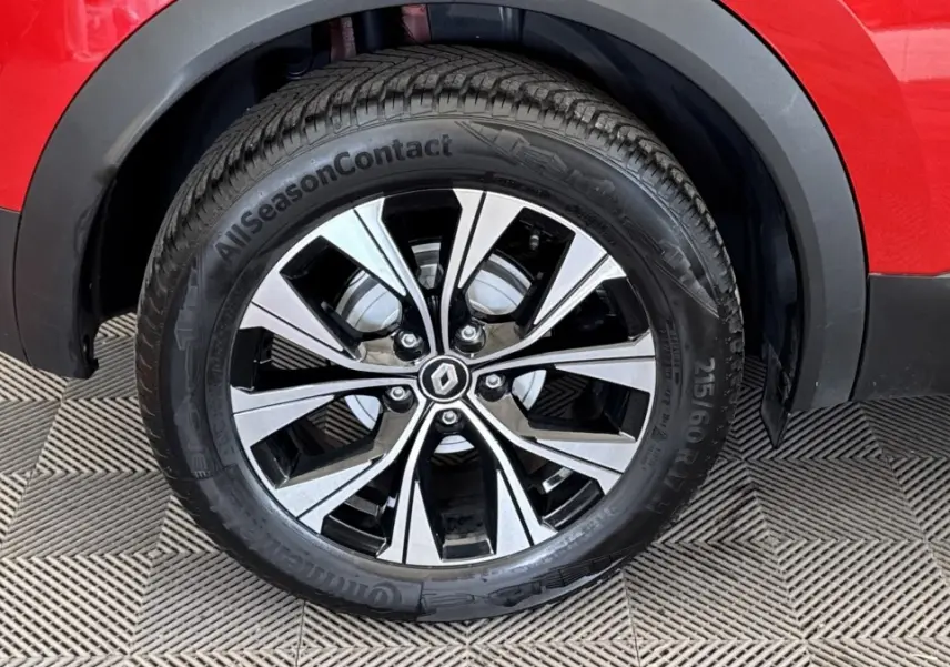 Gros plan sur la roue avant droite du Renault Captur rouge 2024 avec jante alliage bicolore et logo Renault central.