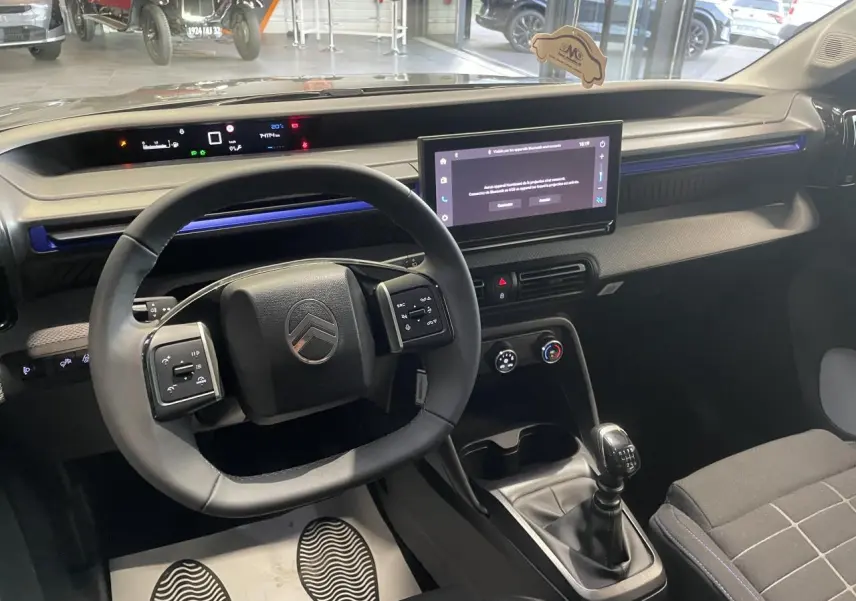 Intérieur de Citroën C3 2025 vu côté conducteur, volant multifonctions, écran tactile 10,25" et levier de vitesse manuel.