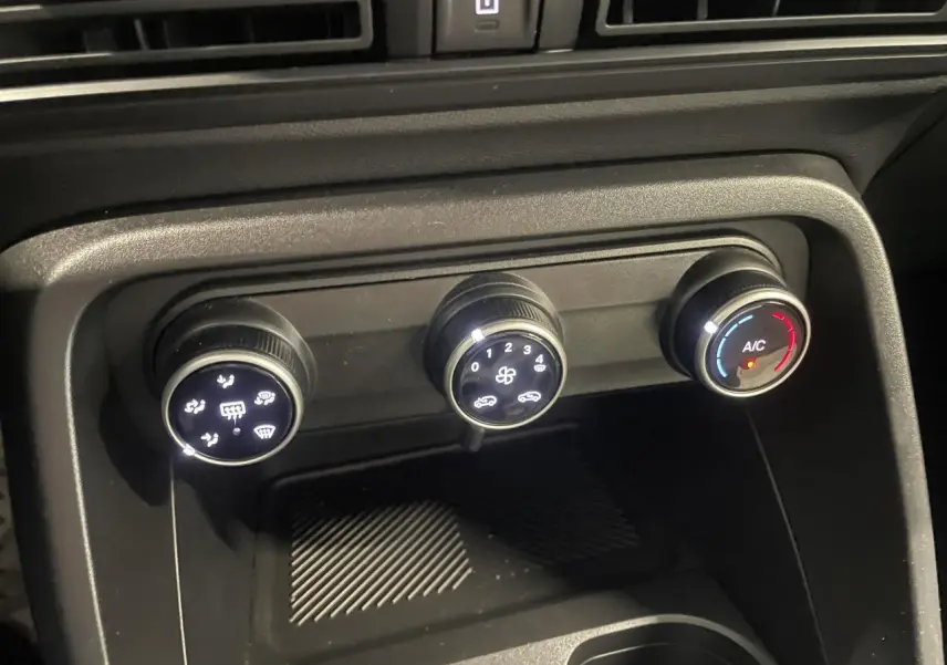 Gros plan sur les commandes de climatisation manuelle de la Citroën C3 2025, boutons noirs avec éclairage blanc.