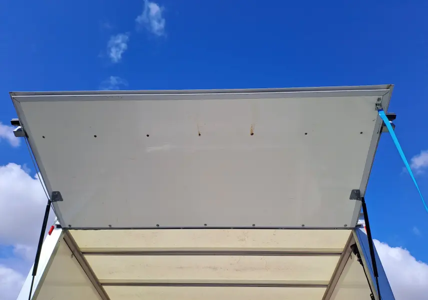 Vue de dessous de la porte arrière blanche ouverte du Nissan Interstar Châssis Cabine L3H1 2024, ciel bleu en arrière-plan.