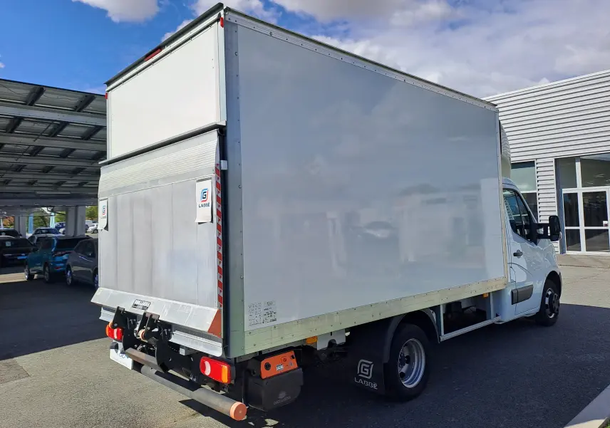 Vue 3/4 arrière droite d’un utilitaire blanc Nissan Interstar Châssis Cabine 2024 avec caisse fermée et hayon élévateur.