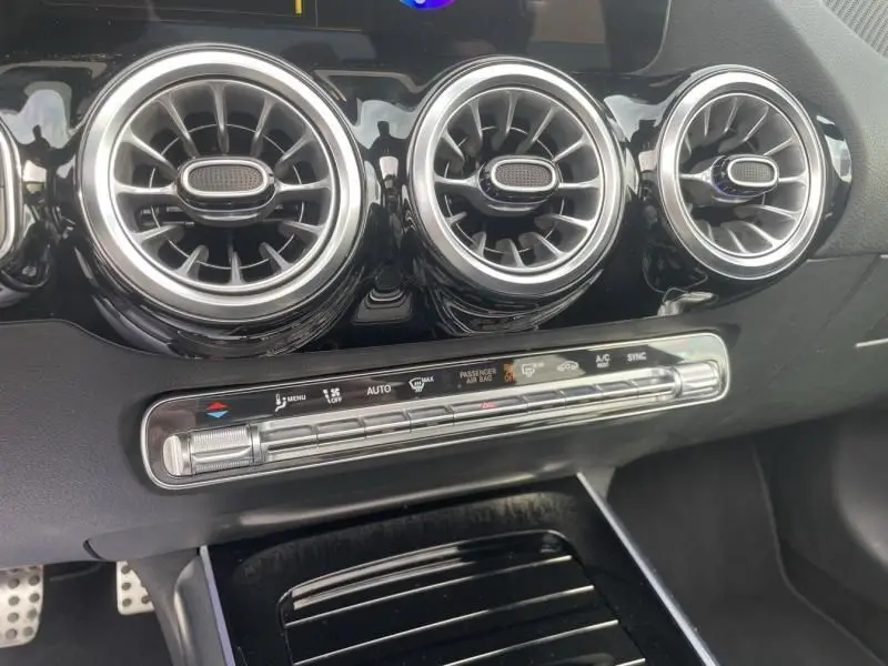 Détail du tableau de bord noir brillant du Mercedes GLA 200 D AMG-LINE 2022, avec ses trois aérateurs ronds chromés.