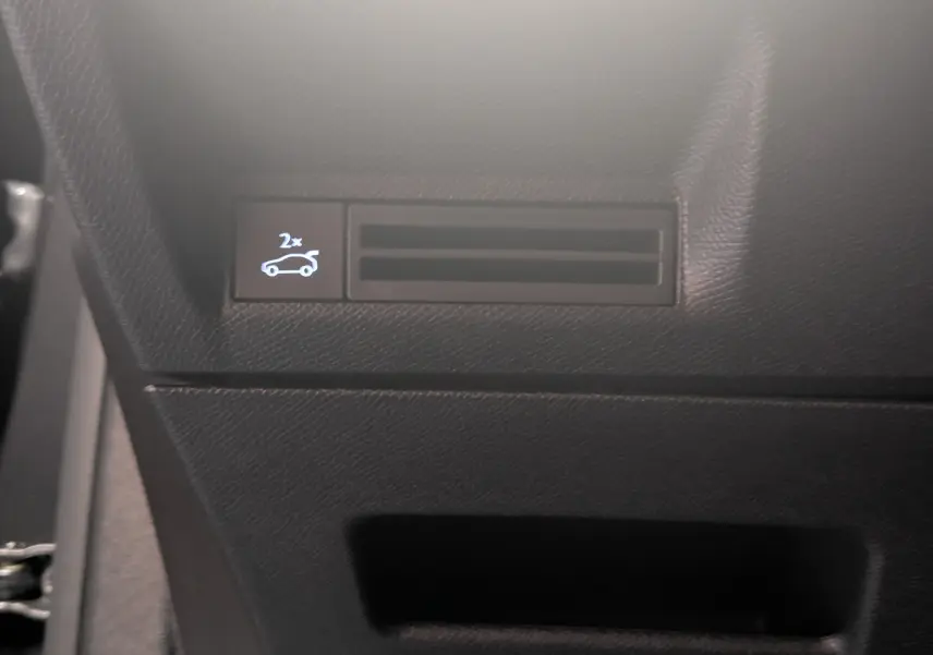 Détail du tableau de bord côté gauche du Peugeot 3008 Hybrid 145 GT 2025 avec bouton d'ouverture du coffre visible.