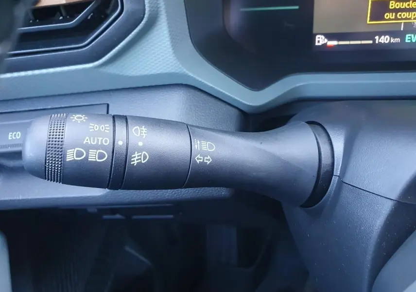 Gros plan sur la commande des feux et clignotants du Dacia Duster 2026 gris schiste, avec affichage digital partiel.