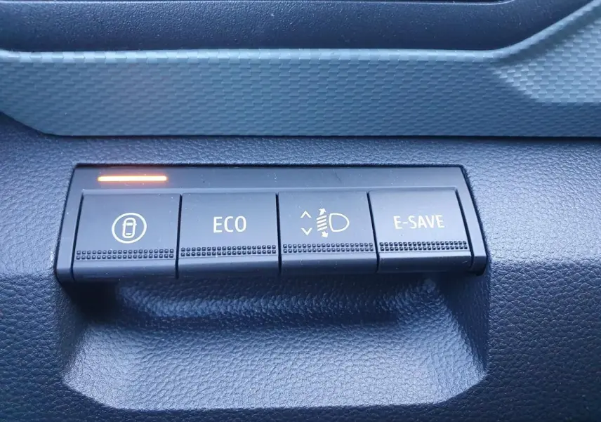 Gros plan sur les boutons de commande du tableau de bord du Dacia Duster gris schiste, avec témoin lumineux orange.