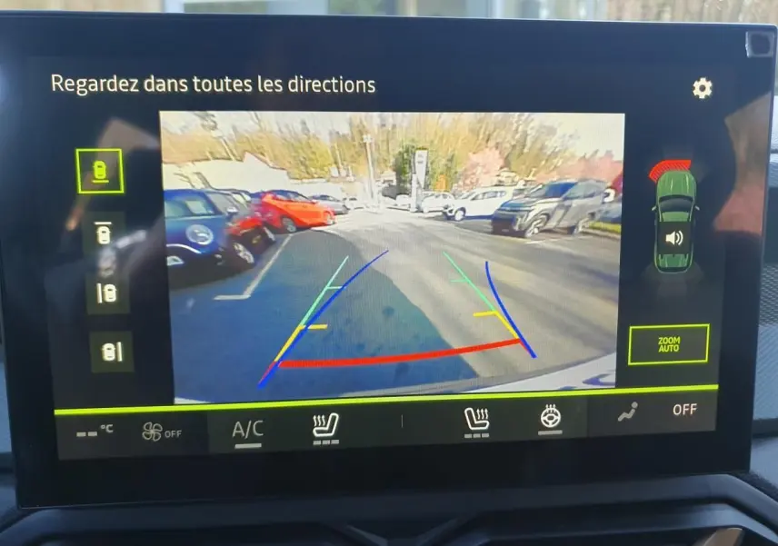 Vue de l'écran de caméra de recul du Dacia Duster 2026, montrant l'arrière et les lignes de guidage colorées.
