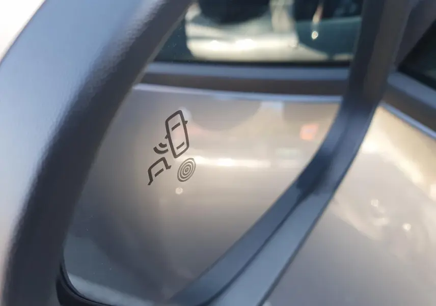 Détail du rétroviseur droit du Dacia Duster gris schiste 2026 avec icône d’alerte de changement de file.