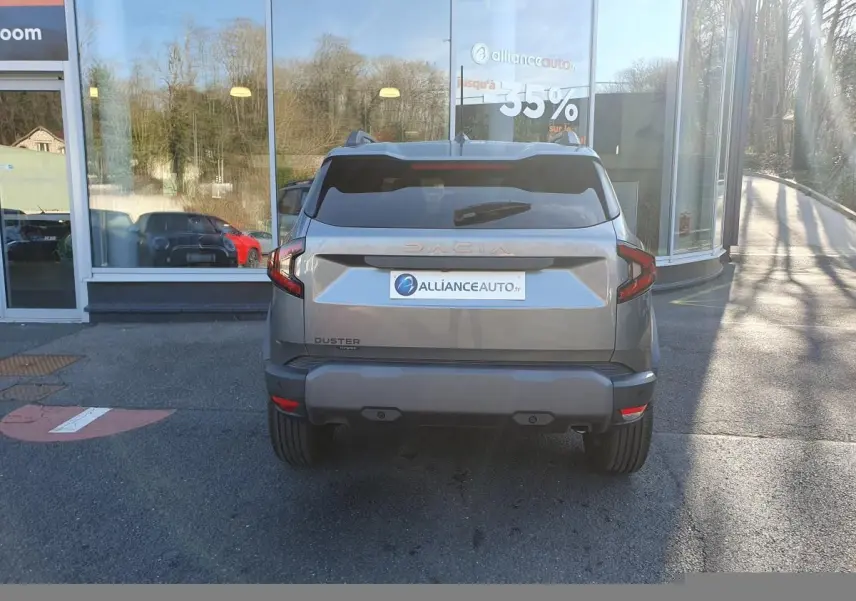 Vue arrière d'un Dacia Duster gris schiste 2026 avec logo Dacia lumineux et feux arrière LED distinctifs.