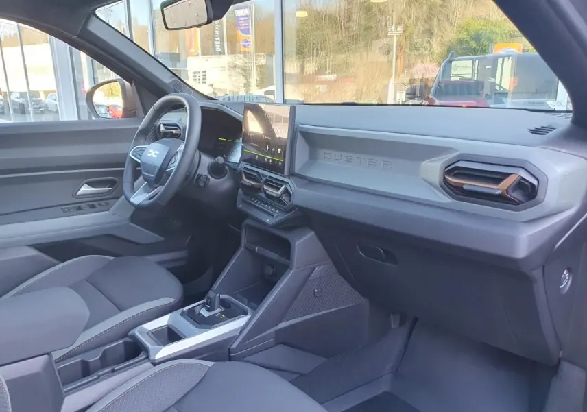 Vue intérieure côté conducteur du Dacia Duster 2026 gris schiste, avec tableau de bord moderne et écran tactile central.