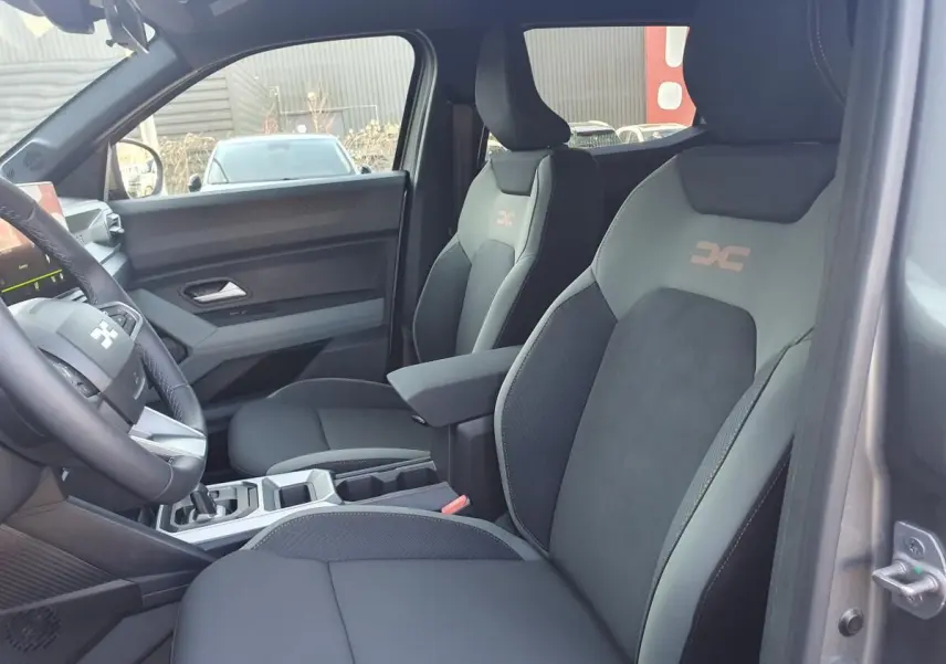 Vue intérieure côté droit du Dacia Duster 1.6 Hybrid gris schiste, sièges avant avec logo "Extreme" et accoudoir central.