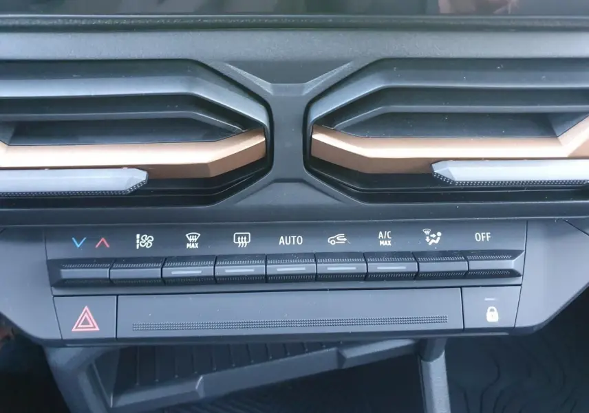 Détail de la console centrale du Dacia Duster 2026 montrant les commandes de climatisation automatique et les aérateurs noirs avec inserts bronze.