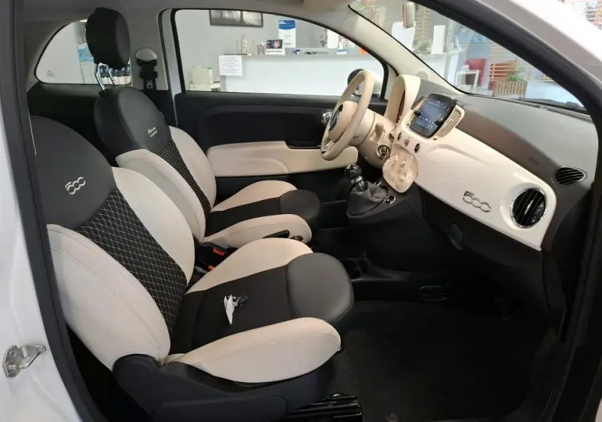 Vue intérieure côté conducteur de la FIAT 500 Dolcevita 2022 en Bossa Nova White, sièges bicolores noirs et beige avec logo 500 brodé.