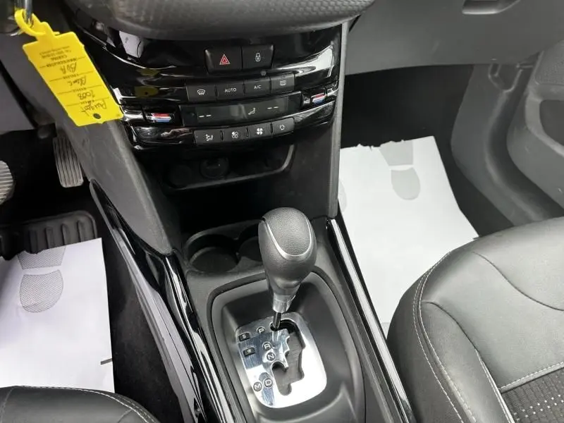 Vue rapprochée de la console centrale du Peugeot 2008 blanc 2019, mettant en valeur le levier de vitesse automatique et les commandes de climatisation.
