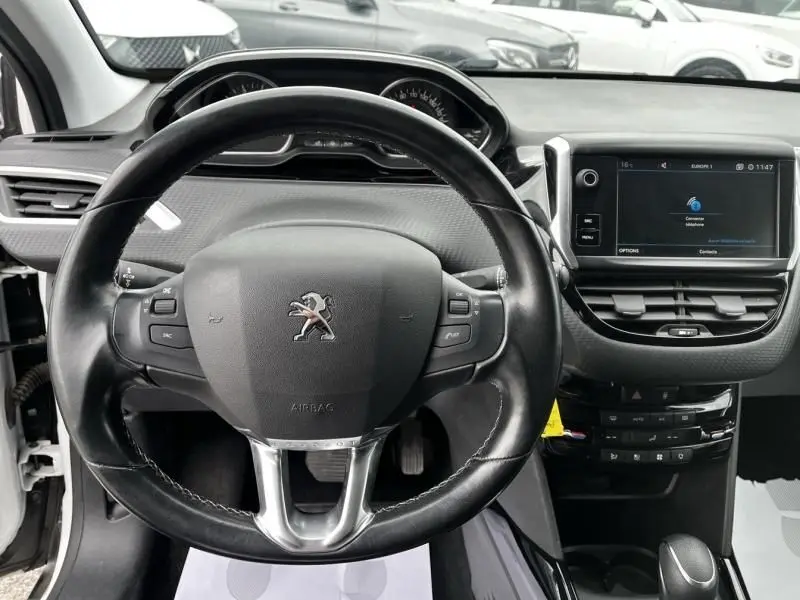 Vue intérieure centrée sur le volant noir du Peugeot 2008 blanc de 2019 avec tableau de bord et écran tactile.