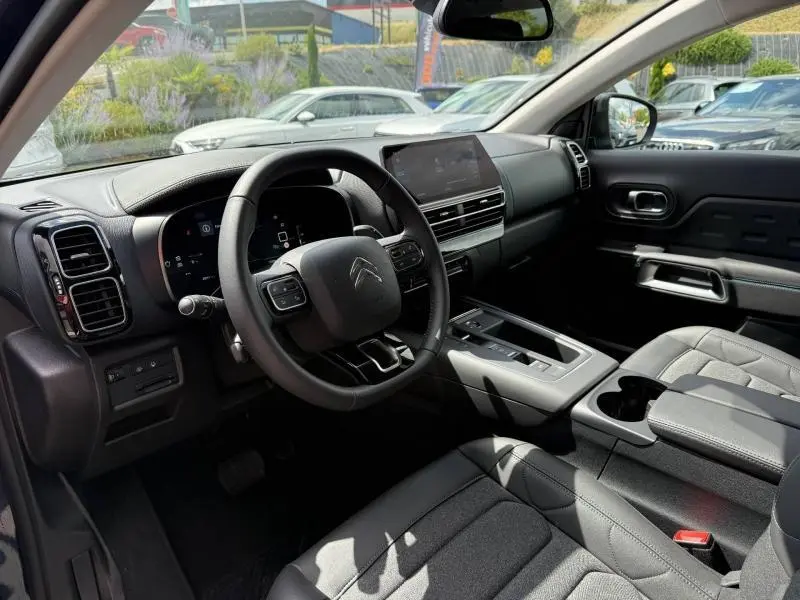 Intérieur noir du Citroën C5 Aircross 2025, vue côté conducteur sur le tableau de bord et la console centrale moderne.