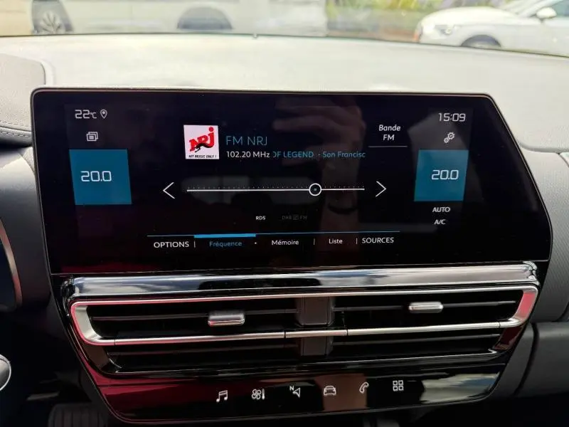 Tableau de bord de Citroën C5 Aircross 2025, affichage numérique central avec radio FM et commandes climatisation visibles.