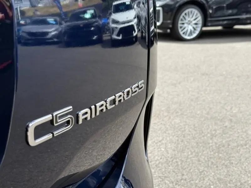 Gros plan sur l'arrière droit bleu foncé du Citroën C5 Aircross 2025 avec le logo du modèle en relief chromé.