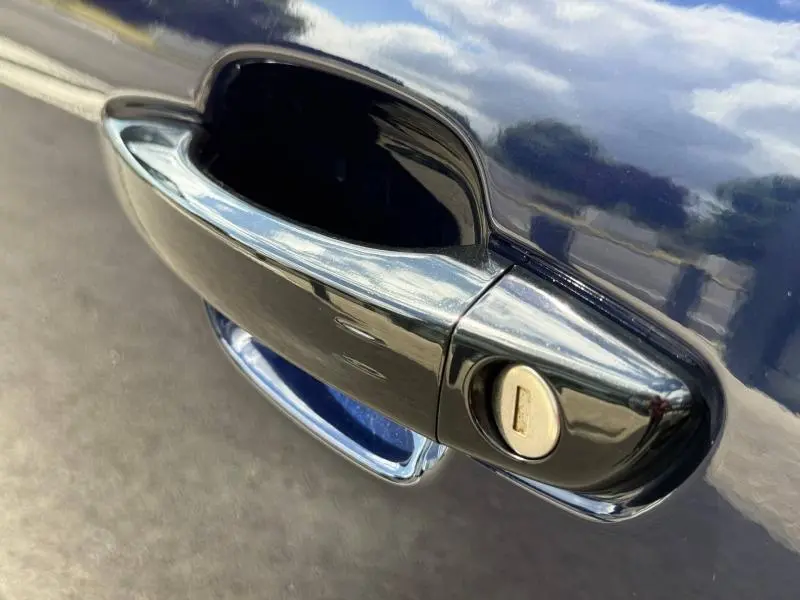 Gros plan sur la poignée de porte noire du Citroën C5 Aircross 2025, version hybride, avec serrure visible sur carrosserie bleue.
