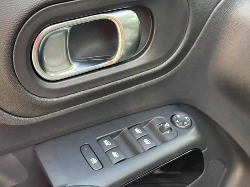 Gros plan sur la poignée intérieure chromée et les commandes de vitres électriques sur la porte côté gauche noire du Citroën C5 Aircross 2025.