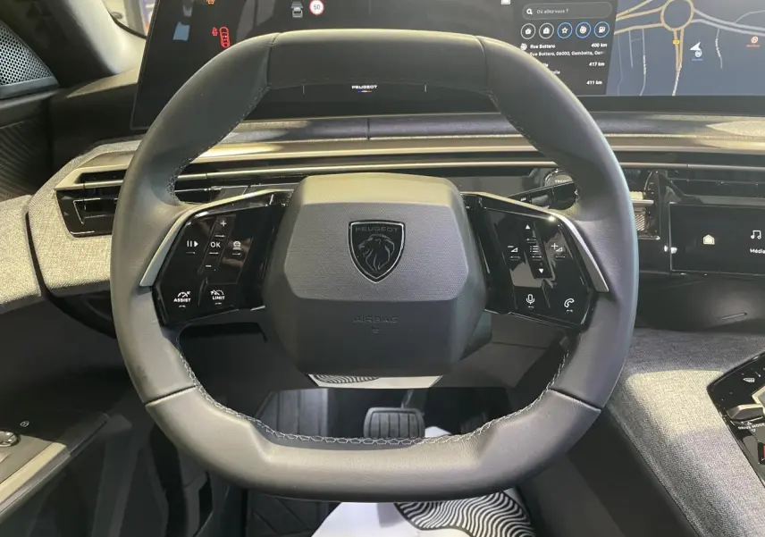 Vue rapprochée du volant cuir noir du Peugeot 3008 2025 avec commandes intégrées et tableau de bord numérique panoramique.