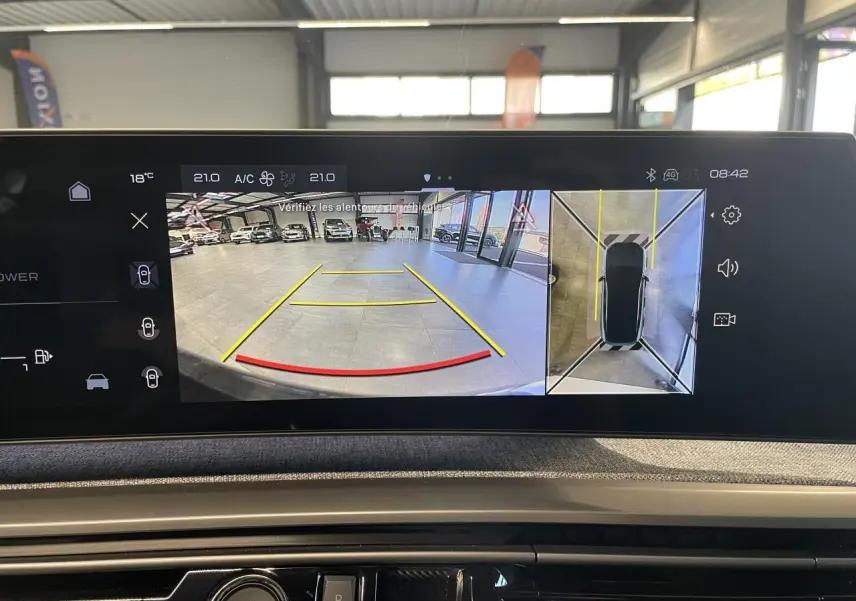 Écran intérieur du Peugeot 3008 montrant la caméra de recul et la vue 360 en garage lumineux.