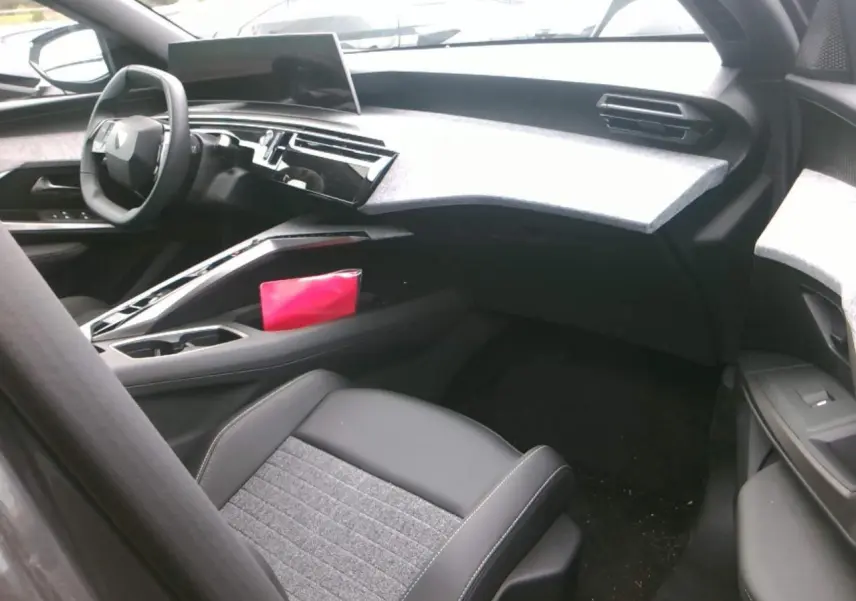 Intérieur avant droit du Peugeot 3008 2025 hybride, avec tableau de bord gris clair et sièges tissu et cuir noirs.