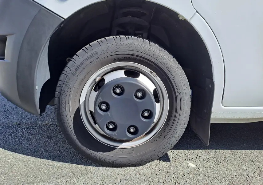 Gros plan sur la roue avant droite du Nissan Interstar blanc, mettant en valeur le pneu Continental et l'aile en plastique noir.