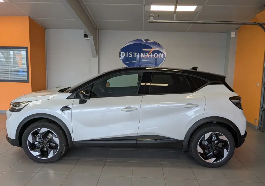 Profil droit du Renault Captur E-Tech Full Hybrid 160ch 2025 blanc nacré avec toit noir et jantes bicolores en showroom.
