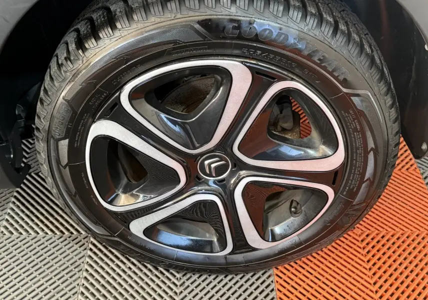 Gros plan sur la roue avant droite de la Citroën C3 gris clair avec jante alliage noire et argentée au logo Citroën.