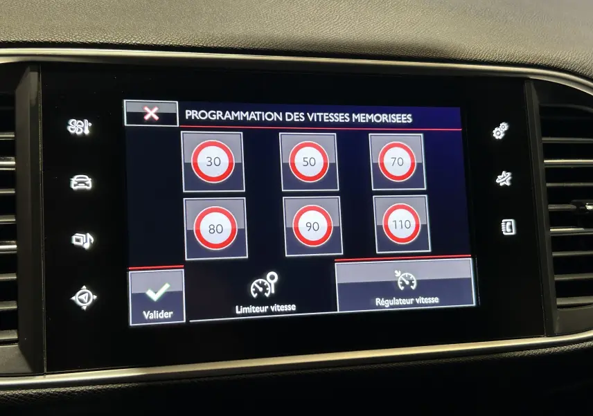 Écran tactile intérieur de la Peugeot 308 noir, affichant la programmation des vitesses mémorisées du régulateur.