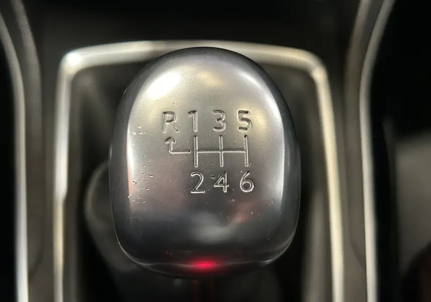 Gros plan sur le pommeau de la boîte manuelle argentée de la Peugeot 308 noire, version 1.6 BlueHDi 120ch GT Line.