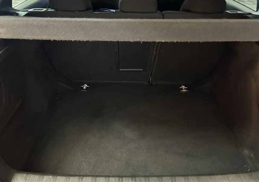 Coffre vide vu de l'arrière d'une Peugeot 308 noire, montrant l'espace de chargement et la banquette arrière.