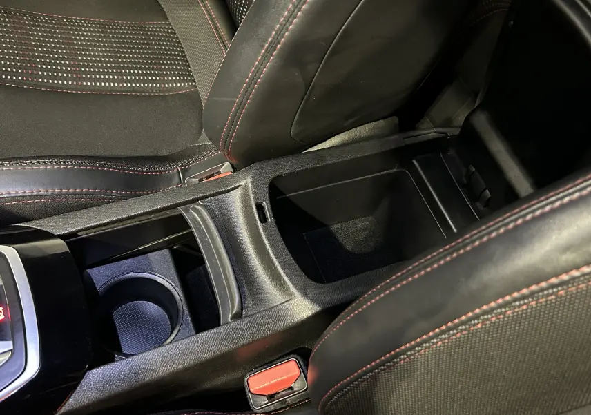 Vue rapprochée de la console centrale noire avec rangement ouvert et surpiqûres rouges des sièges Peugeot 308 GT Line 2017.
