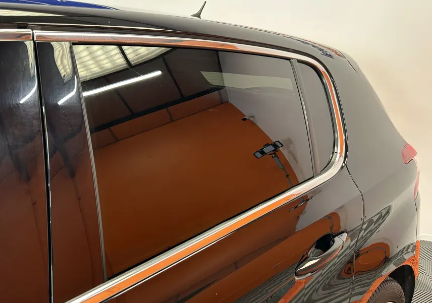 Vue latérale droite sur la partie arrière d’une Peugeot 308 noire avec vitres teintées et jantes visibles.