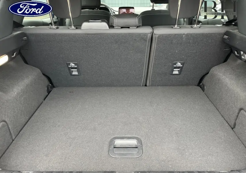 Vue du coffre arrière ouvert du Ford Puma 2023, intérieur tissu noir avec banquette rabattable et ancrages Top Tether.