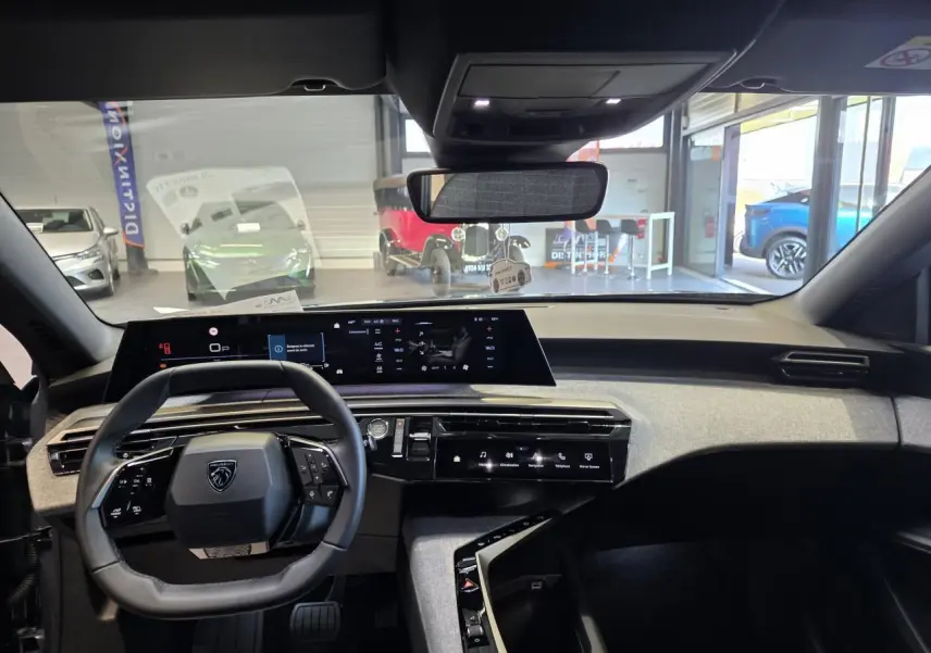 Intérieur Peugeot 3008 2025 vue de face sur le tableau de bord avec volant compact noir et écran panoramique incurvé.